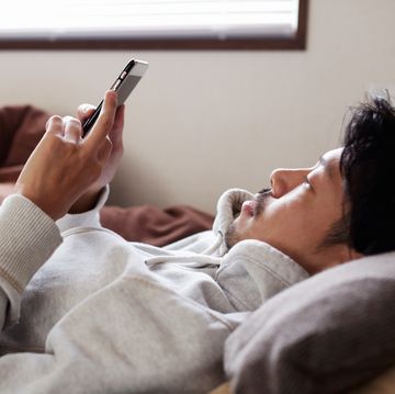young man using smart phone lying on bed