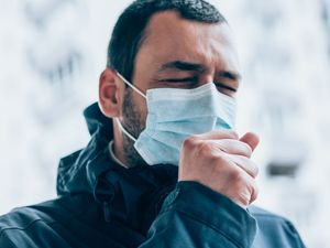 young man wear face mask and coughing outdoors