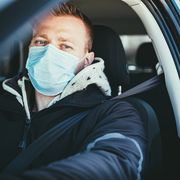 COVID-19, Young man wearing disposable face mask while driving