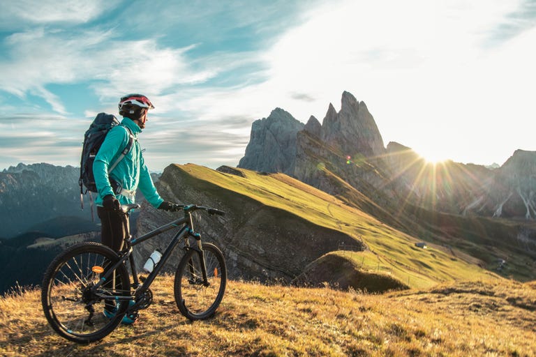 giovane con la mountain bike sulla vetta del monte seceda all'alba puez odle, trentino, dolomiti, italia