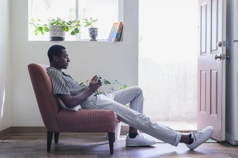 young man with phone sitting in chair in his home