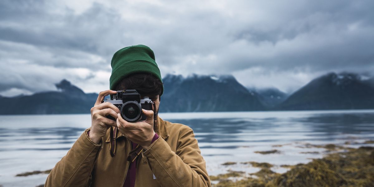 young man with woolly hat taking pictures with camera