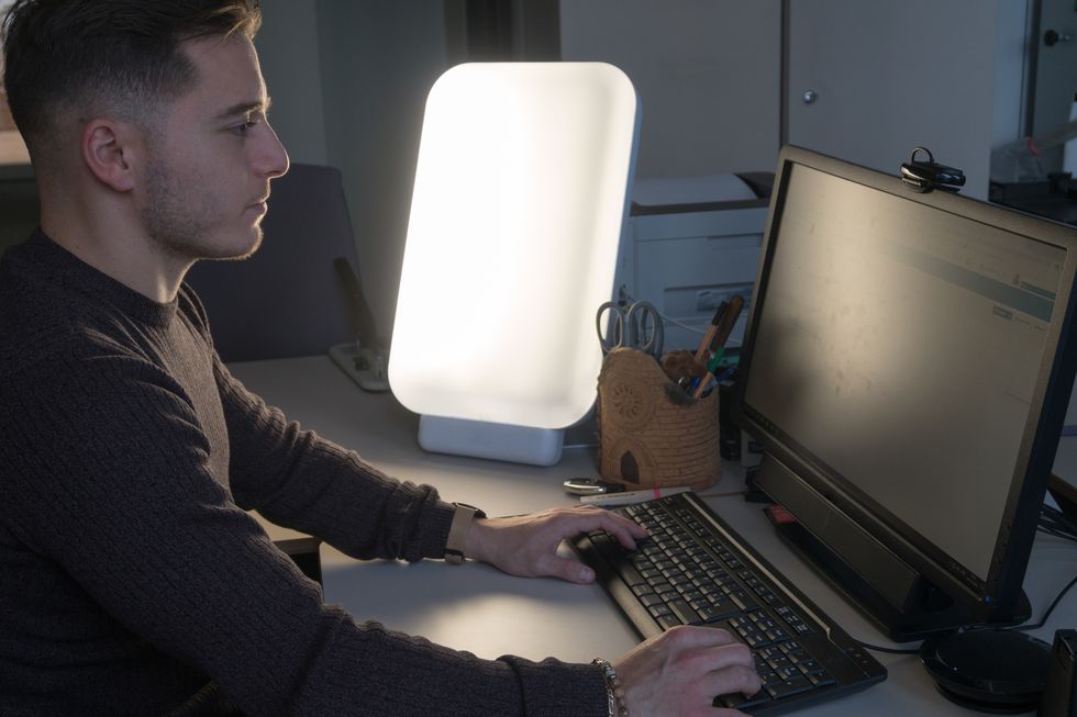 young man working at the office with light therapy lamp
