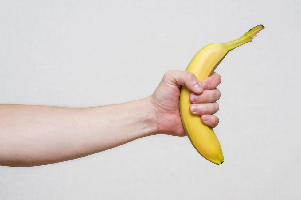 young man's hand holding a beautiful, fresh, yellow banana male hand holding a banana