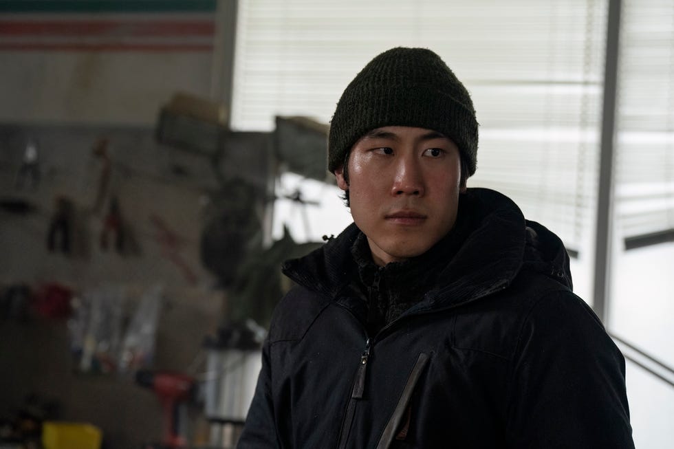 a person wearing a black jacket and a green beanie in a workshop setting