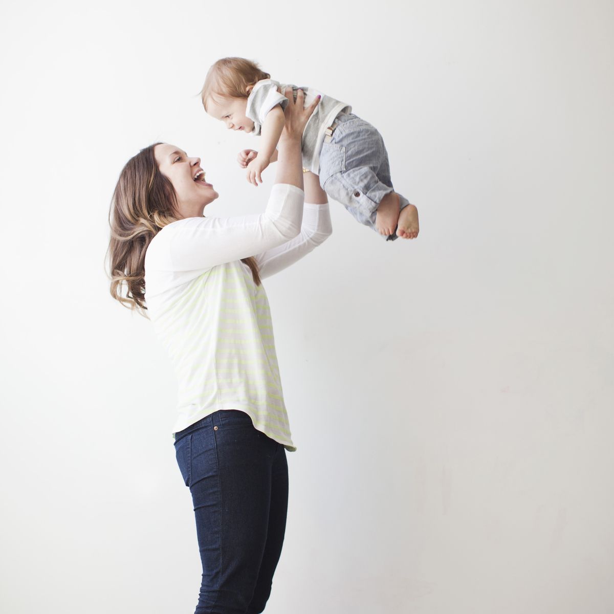 young mother lifting baby boy 6 11 months mid air