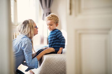 a young mother talking to her toddler son inside in a bedroom