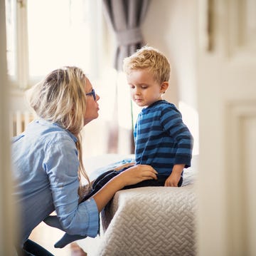 A young mother talking to her toddler son inside in a bedroom. a young mother talking to her toddler son inside in a bedroom