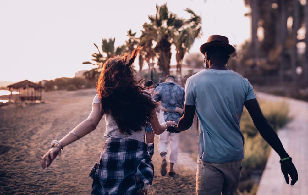 Young multi-ethnic couples walking on tropical island beach at sunset
