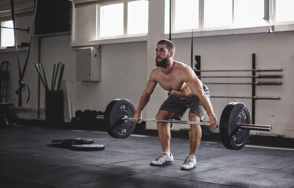 young muscular bearded man weightlifter exercise with barbell