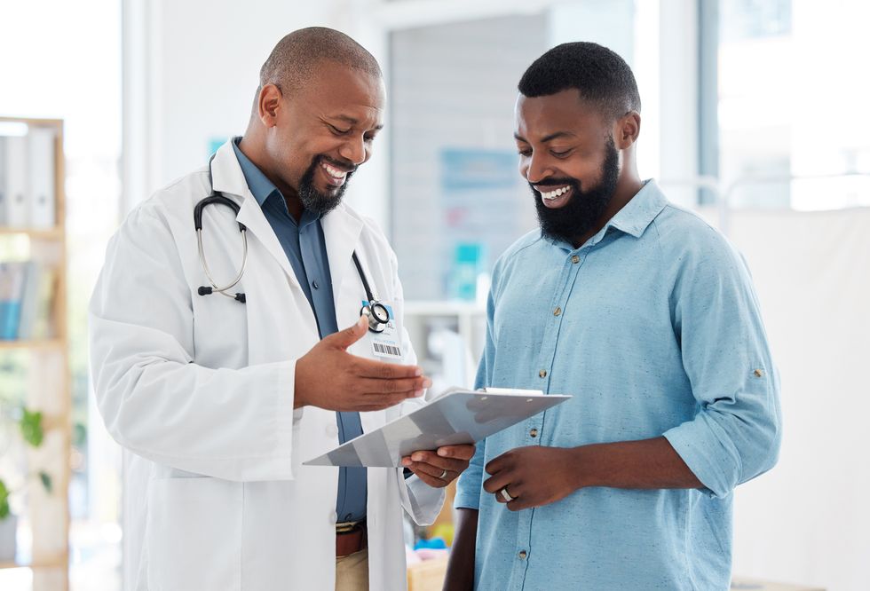 young patient in a consult with his doctor african american doctor showing a patient their results on a clipboard medical professional talking to his patient in a checkup