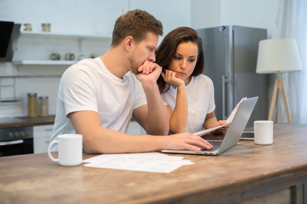 young pensive man and woman using laptop at the kitchen