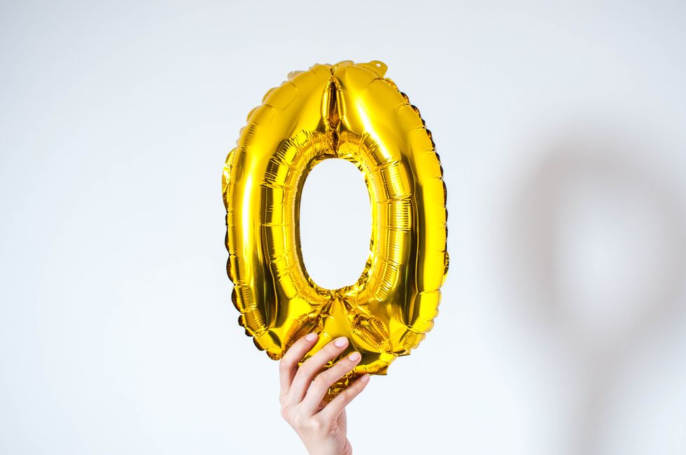 a young person is holding a goldencolored number zero on a white background