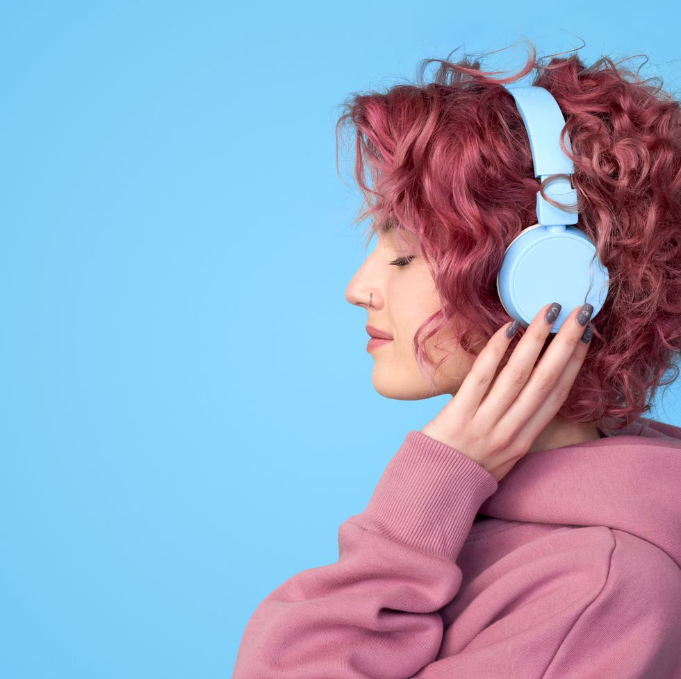 young pink hair girl listening music in headphones