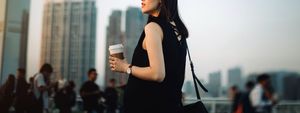 young pregnant woman having coffee and relaxing in city, looking towards the beautiful sky at sunset