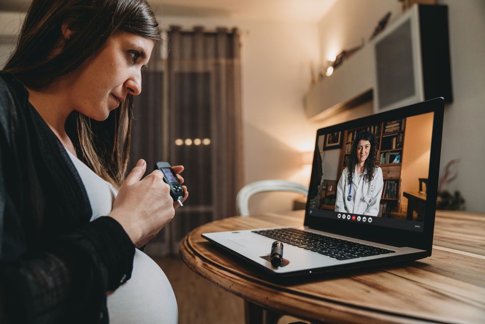 young pregnant woman is having a video call with her female doctor while she's testing her blood sugar curve
