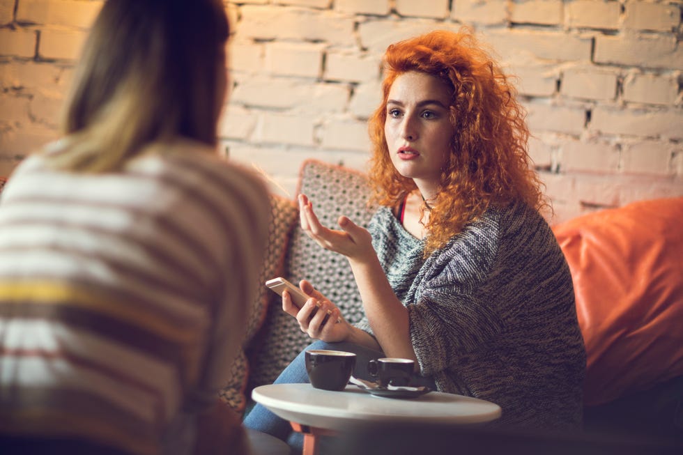young redhead woman discussing with a friend in cafe