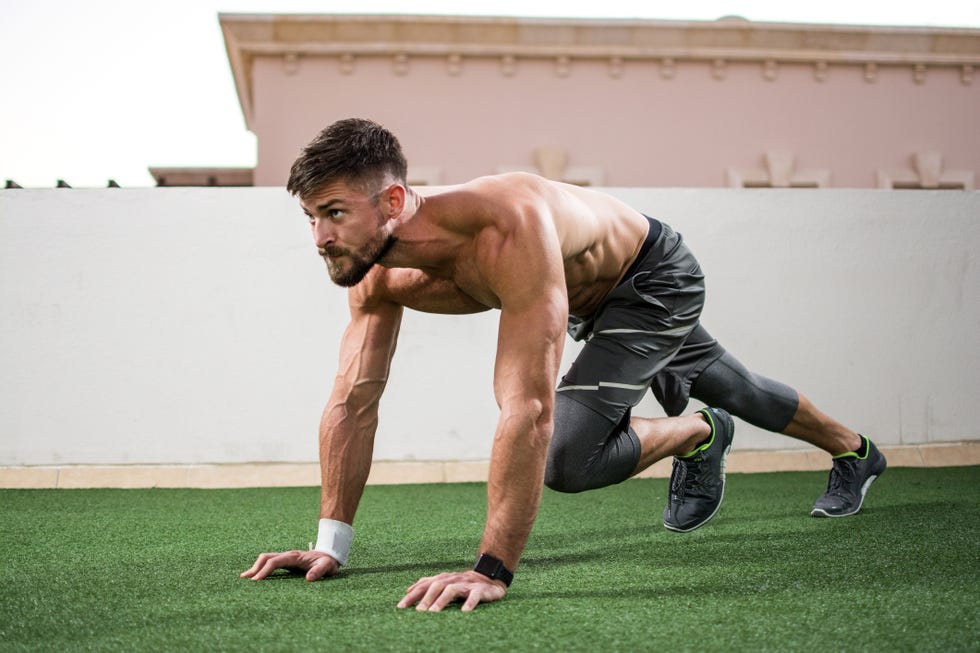 Young shirtless muscular man warming up before a workout outdoors.