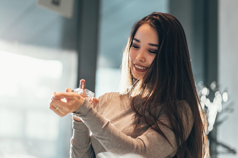 young smiling woman using perfume