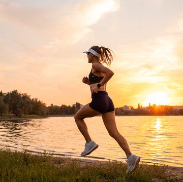 young sportswoman running at sunset by lakeside sports hobby for pleasure