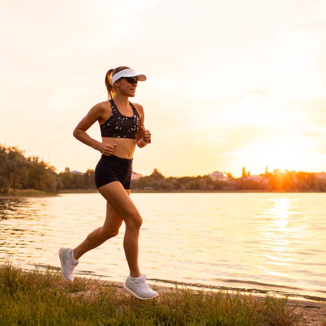 young sportswoman running at sunset by lakeside. sports hobby for pleasure