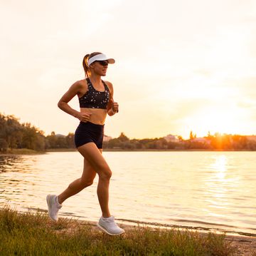 young sportswoman running at sunset by lakeside. sports hobby for pleasure