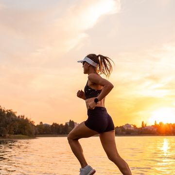 young sportswoman running at sunset by lakeside. sports hobby for pleasure