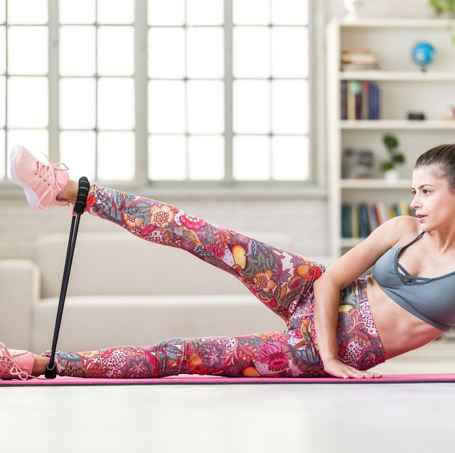 young sporty attractive woman practicing exercise with resistance band at home