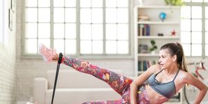 young sporty attractive woman practicing exercise with resistance band at home