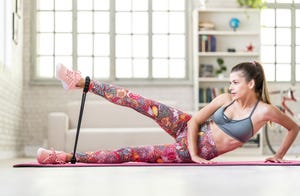 young sporty attractive woman practicing exercise with resistance band at home