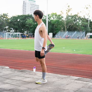 young sporty man stretching on running track