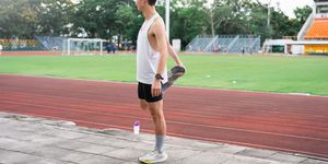 young sporty man stretching on running track