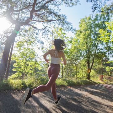 young sporty woman jogging through the forest
