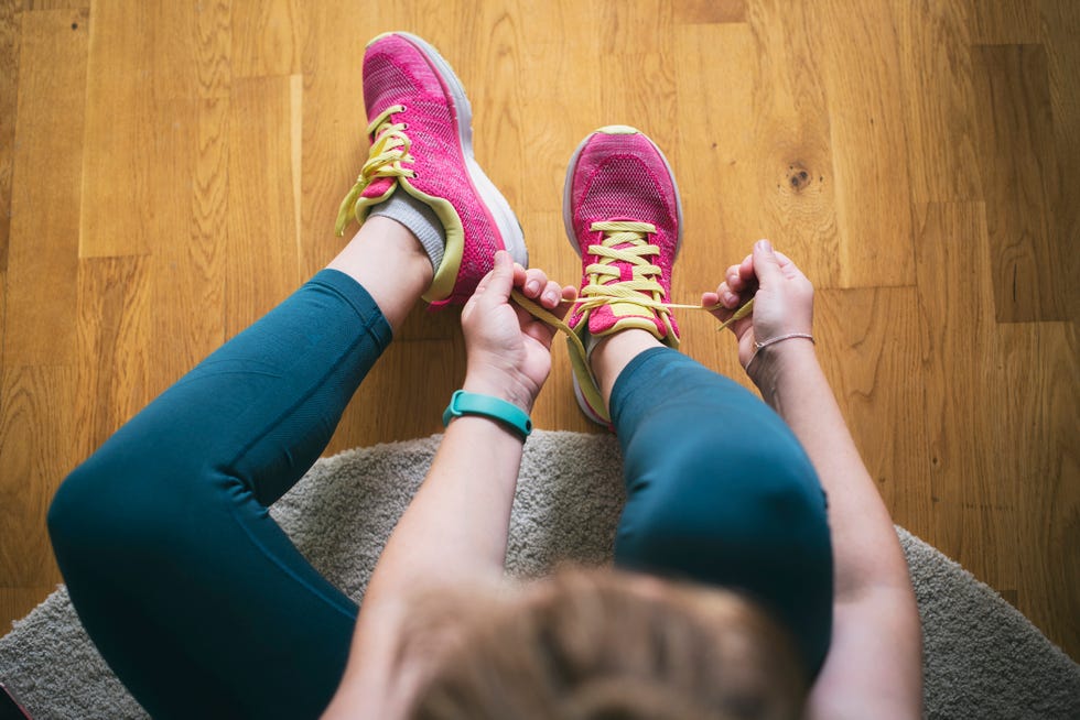 young sporty woman with smart watch tying shoelaces