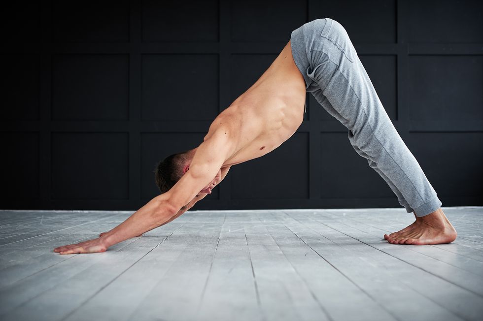 young strong shirtless man practices yoga at the yoga studio