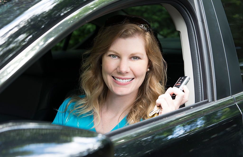 young teenage girl age 16 with first driving of a car showing off her keys