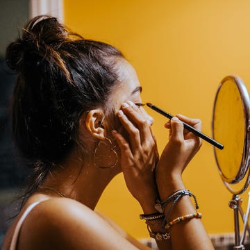 young teenager applying eyeliner in domestic bathroom