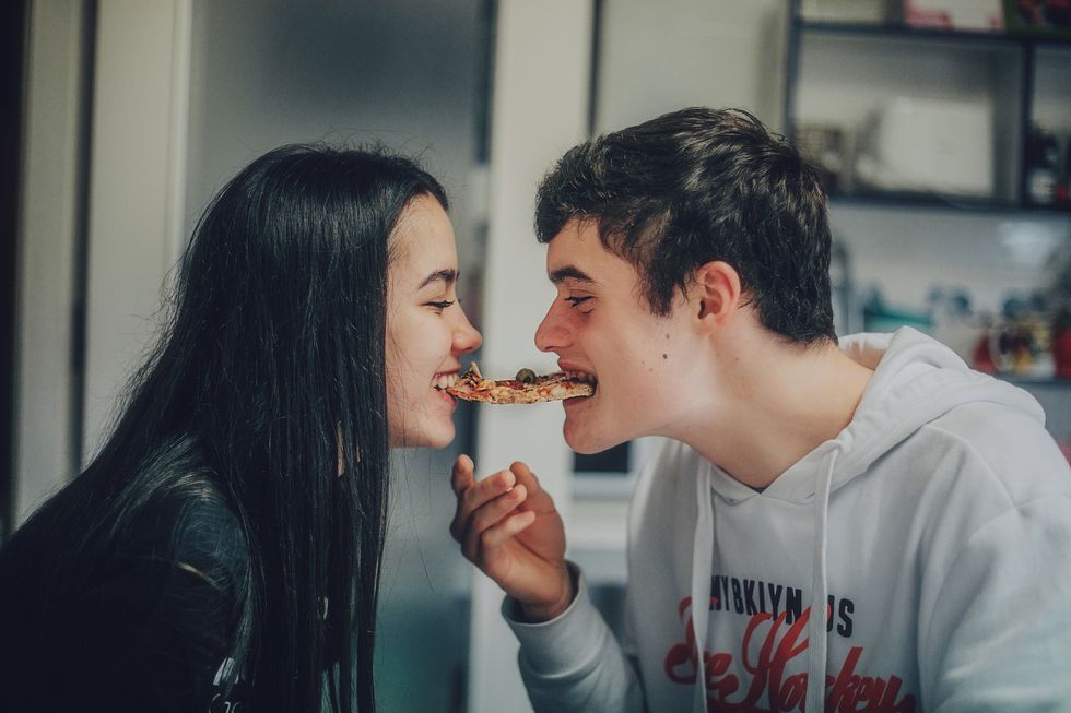 young teenager copule sharing slice  of pizza at home
