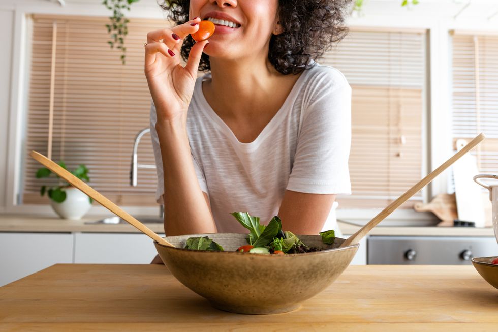 young unrecognisable multiracial african american eating tomato from fresh saladhealthy eating