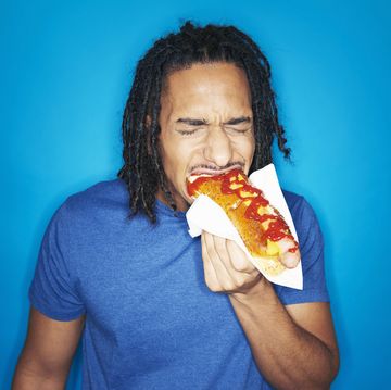 young urban man eating hotdog