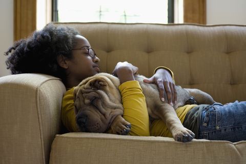 a young woman and her shar pei napping on a couch