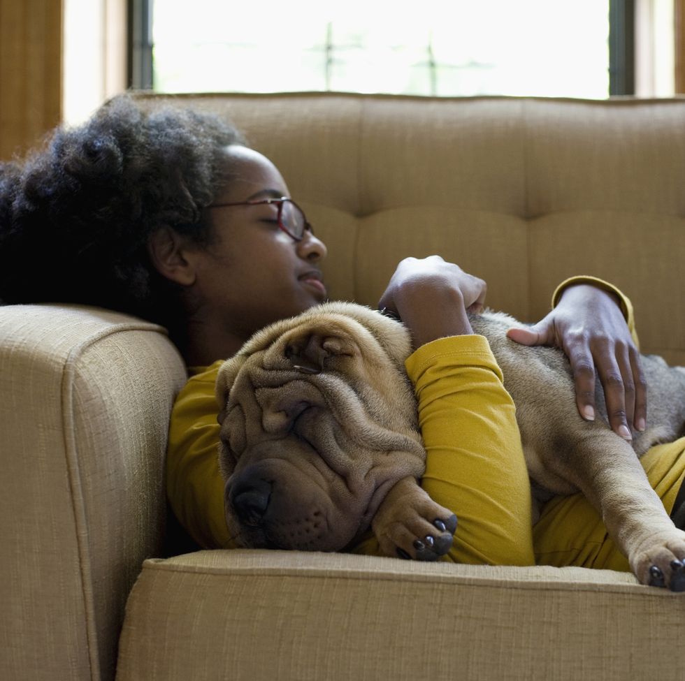 a young woman and her sharpei napping on a couch