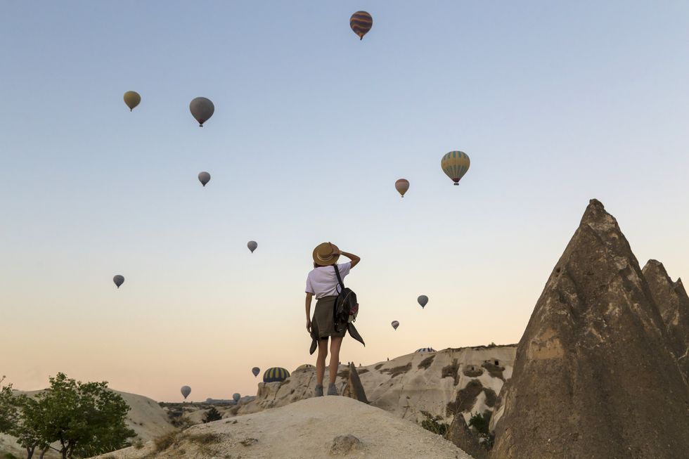 young woman and hot air ballons, goreme, cappadocia, turkey