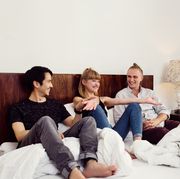 young woman and male friends sitting chatting on bed