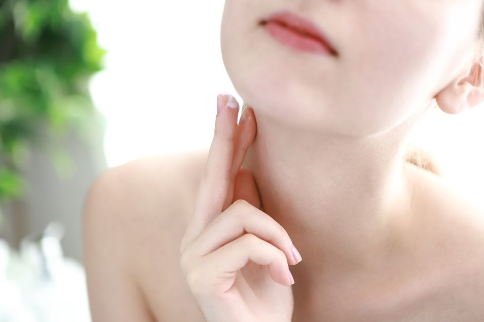 Young woman applying cream on neck
