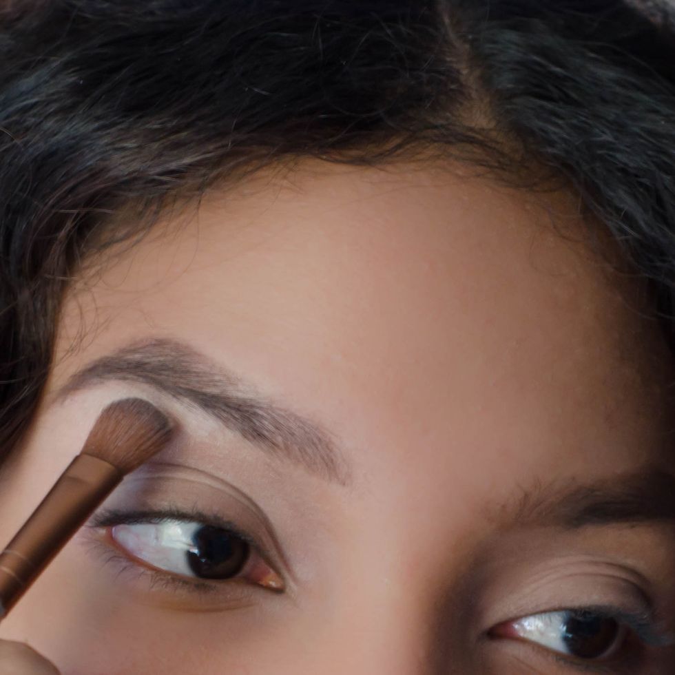 young woman applying eyeshadow to her brow bone