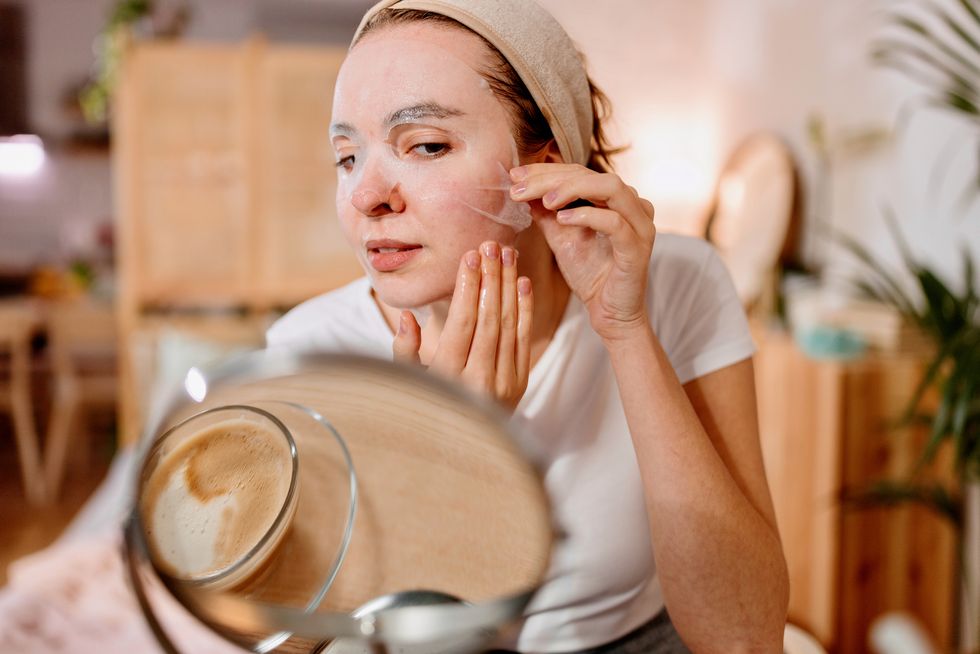 young woman applying face mask at home