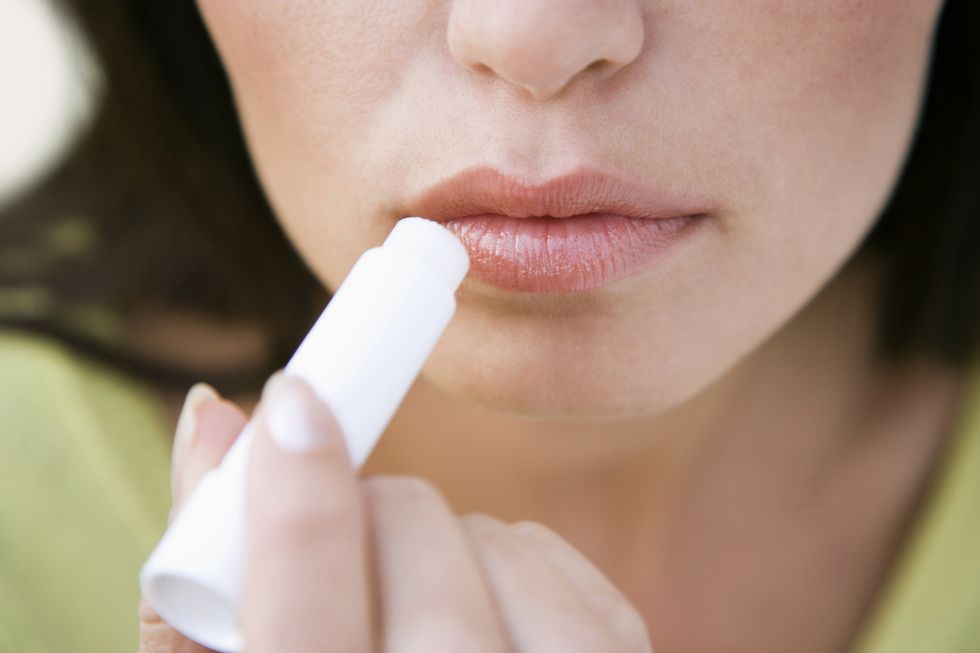 Young woman applying lip balm, close-up