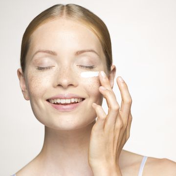 mujer rubia aplicando crema hidratante en la cara