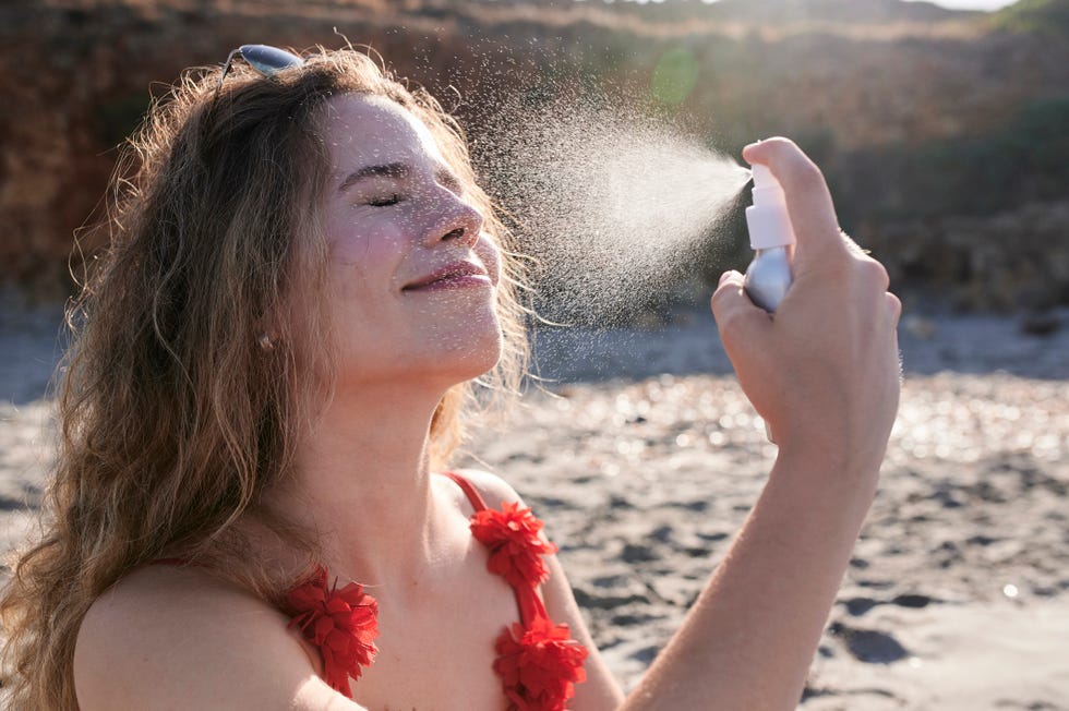 una chica joven se aplica protección solar en el rostro